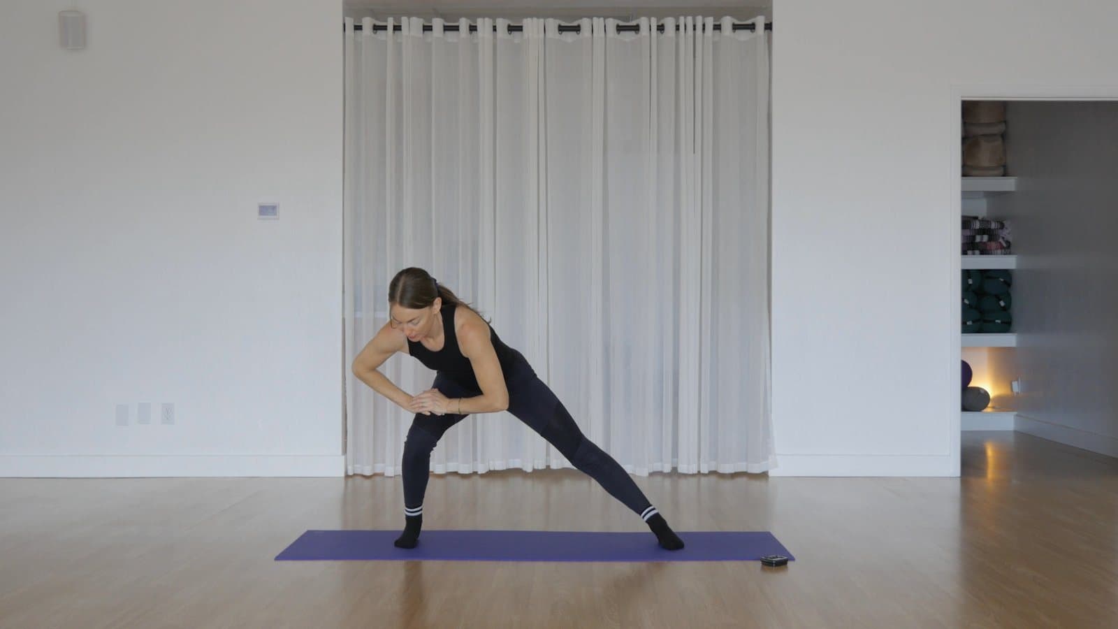 Standing in a wide stance, folding sideways with one hand reaching down the leg